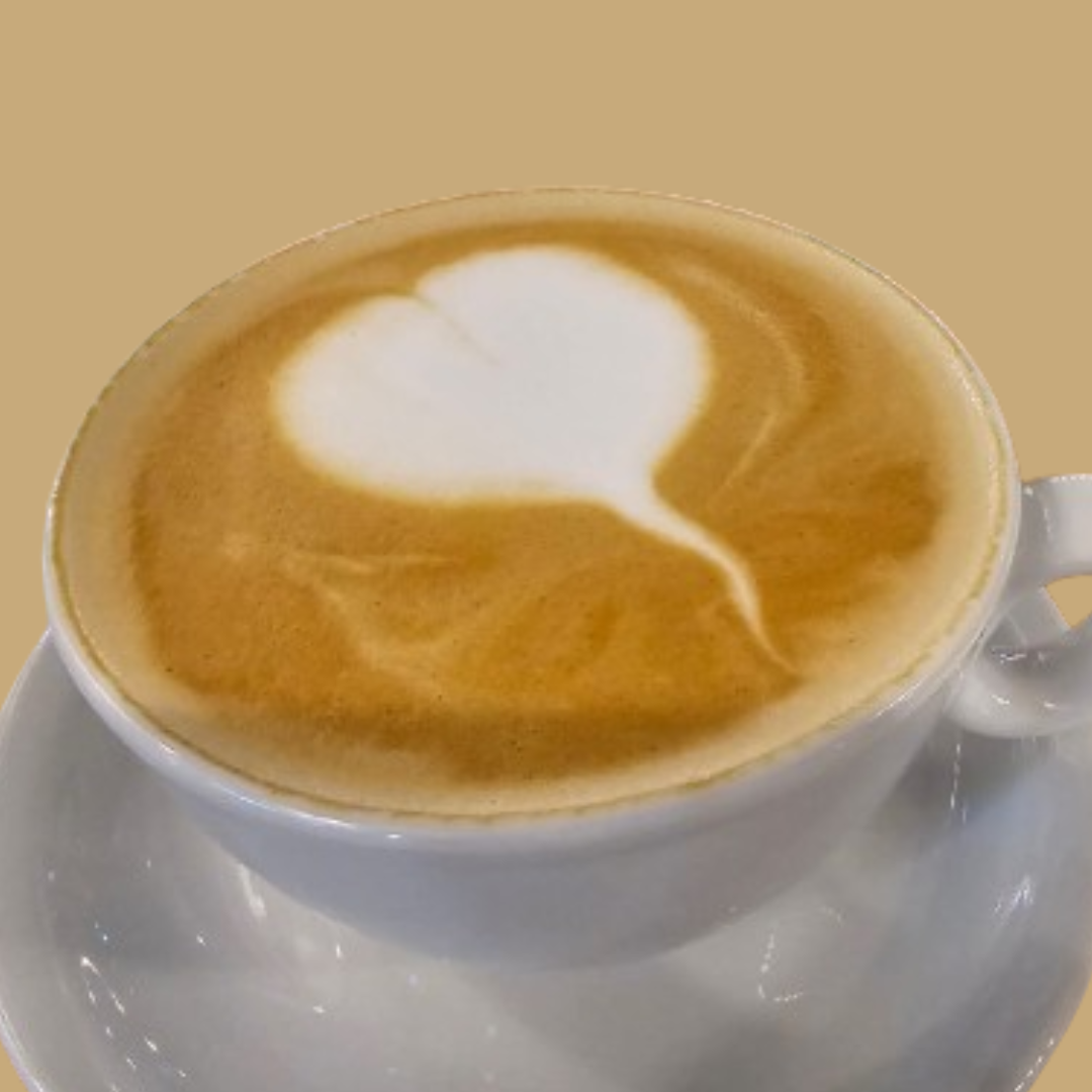 A close-up of a cup of cappuccino with smooth latte art in the shape of a heart, served in a white cup and saucer against a light brown background