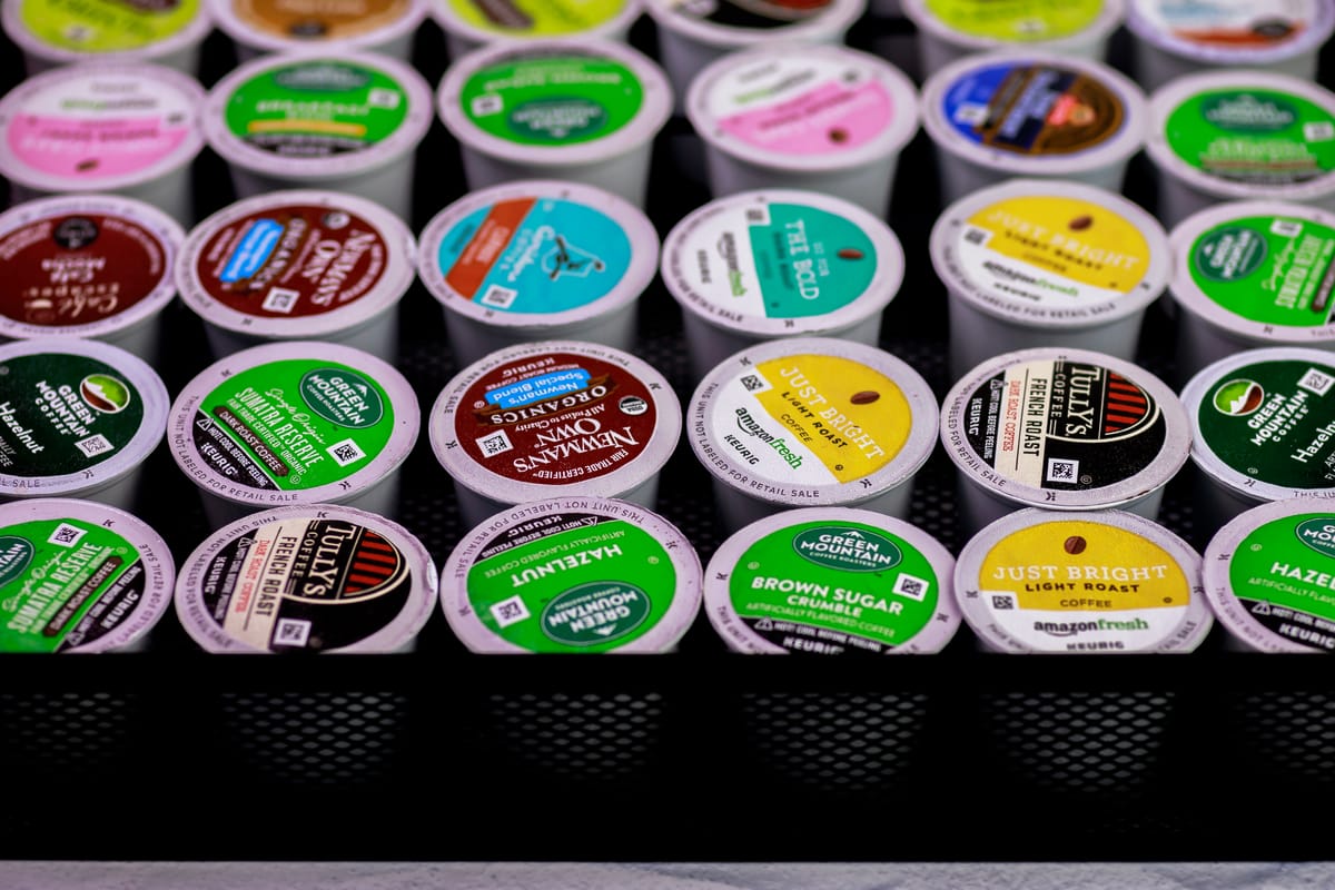A variety of Keurig K-Cup coffee pods arranged neatly in rows, featuring different flavors and brands like Green Mountain, Newman’s Own, and AmazonFresh, photographed by Joice Brinkerhoff.