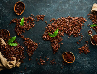 World map made from roasted coffee beans on a dark textured surface, symbolizing the global coffee trade and market connections.