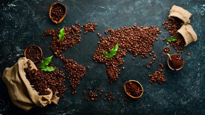 World map made from roasted coffee beans on a dark textured surface, symbolizing the global coffee trade and market connections.