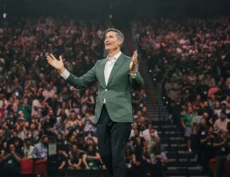 Brian Niccol, CEO of Starbucks, speaking on stage in front of a large audience