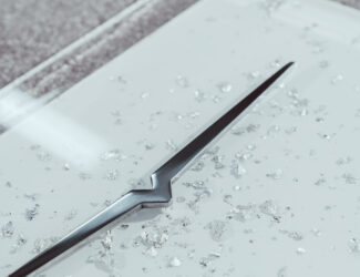 Close-up of a sleek metallic Victoria Arduino design element embedded in a white surface with silver crystal-like fragments, symbolizing luxury craftsmanship and precision.