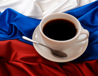 A white cup of black coffee on a saucer with a spoon placed over the Russian flag in red, blue, and white colors.