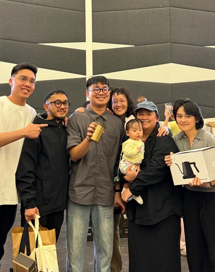 Neil Golez, surrounded by friends and supporters, smiles while holding his AeroPress trophy after being crowned UAE AeroPress Champion 2025 in Dubai.