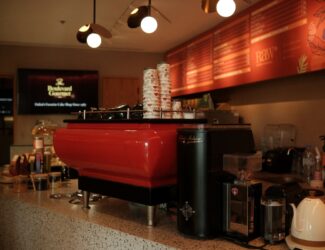 A vibrant red espresso machine inside Boulevard Gourmet café at Radisson Blu Dubai Deira Creek, designed by RAW Coffee Company, showcasing modern specialty coffee culture in Dubai’s historic Creek area.